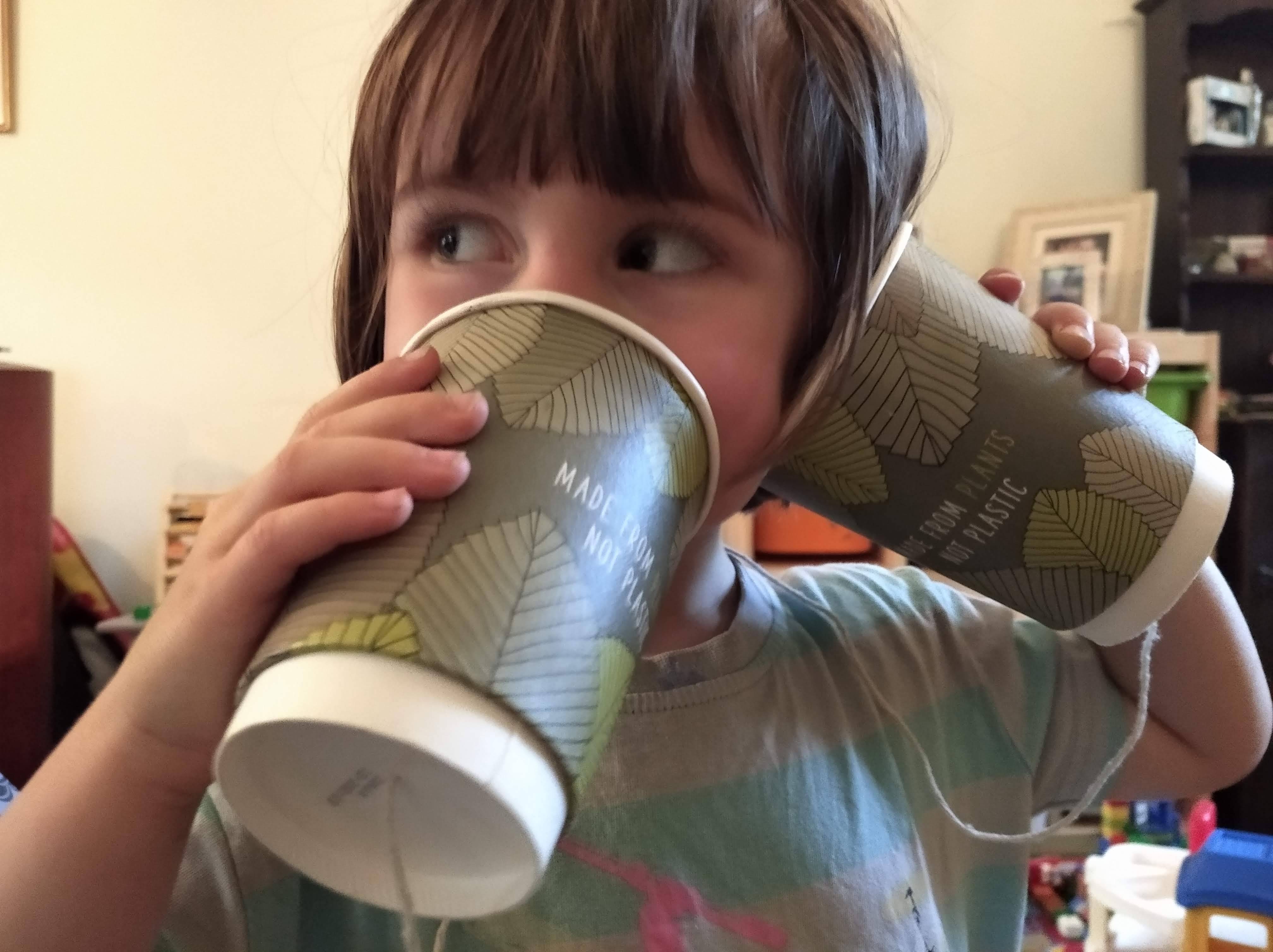 child with a paper cup telephone