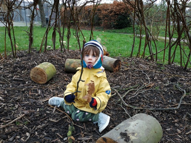 child holding stick in willow wigwam