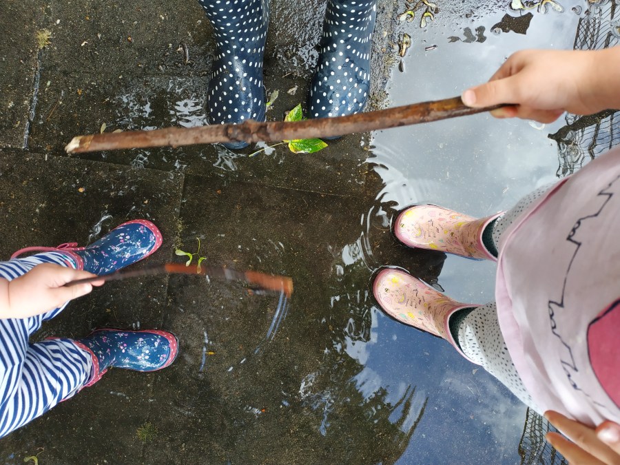 three pairs of feet wearing wellies in a puddle