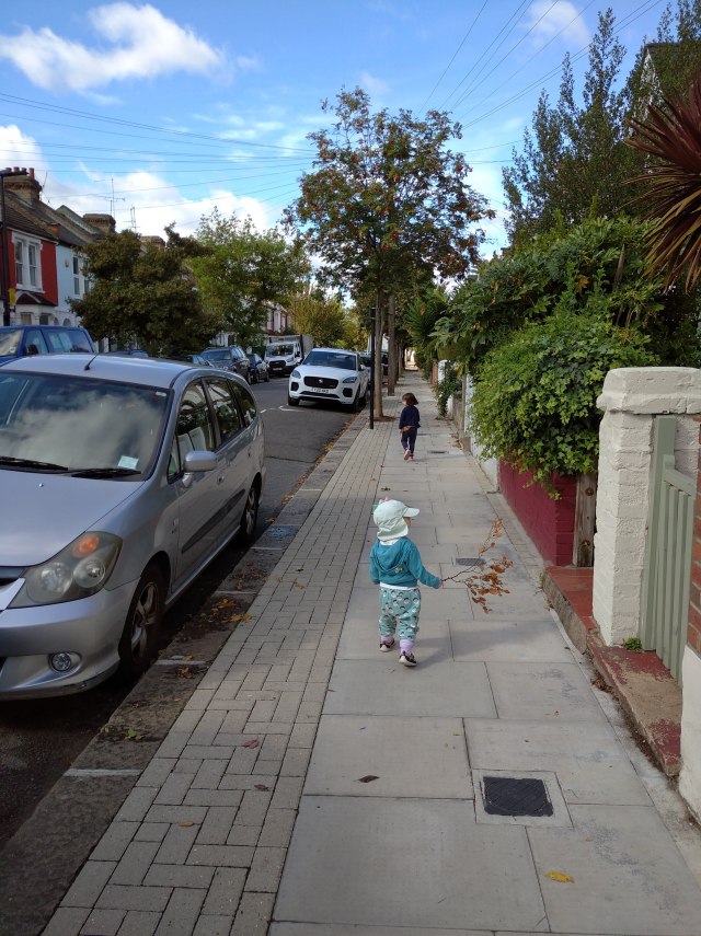 children walking down a road carrying sticks